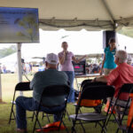 A woman with a microphone presents before a crowd