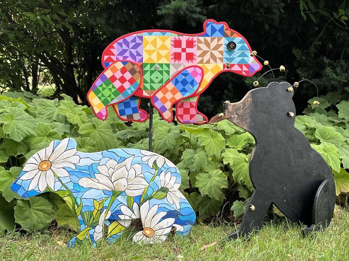 Wood cutouts in the shape of bears. Some are colorful and patterned, while one is realistically colored.
