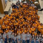 A large group of high-school students wearing orange shirts.