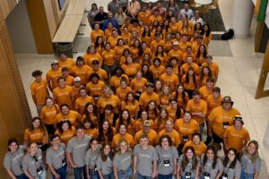 A large group of high-school students wearing orange shirts.