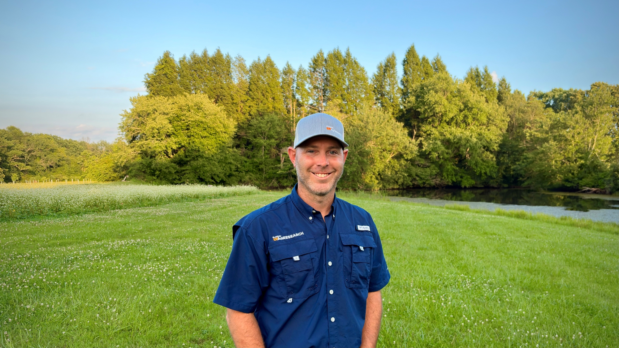 Dereck Corbin standing in a field wearing a blue shirt and a gray hat.