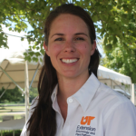 Heather Kelly smiles at the camera while wearing a white collared shirt with an orange "UT" logo