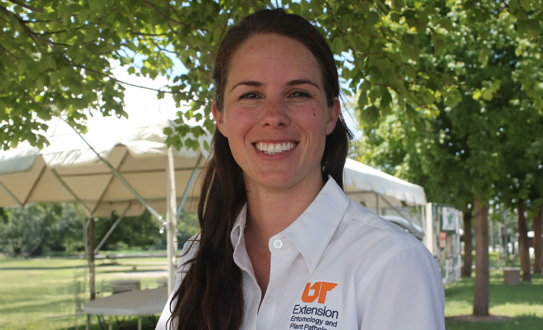 Heather Kelly smiles at the camera while wearing a white collared shirt with an orange "UT" logo