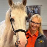 Dr. Carla Sommardahl stand with a white horse.