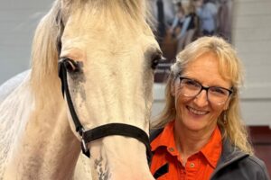 Dr. Carla Sommardahl stand with a white horse.