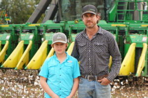 Scott Farmer and his son standing in front of farm machinery,