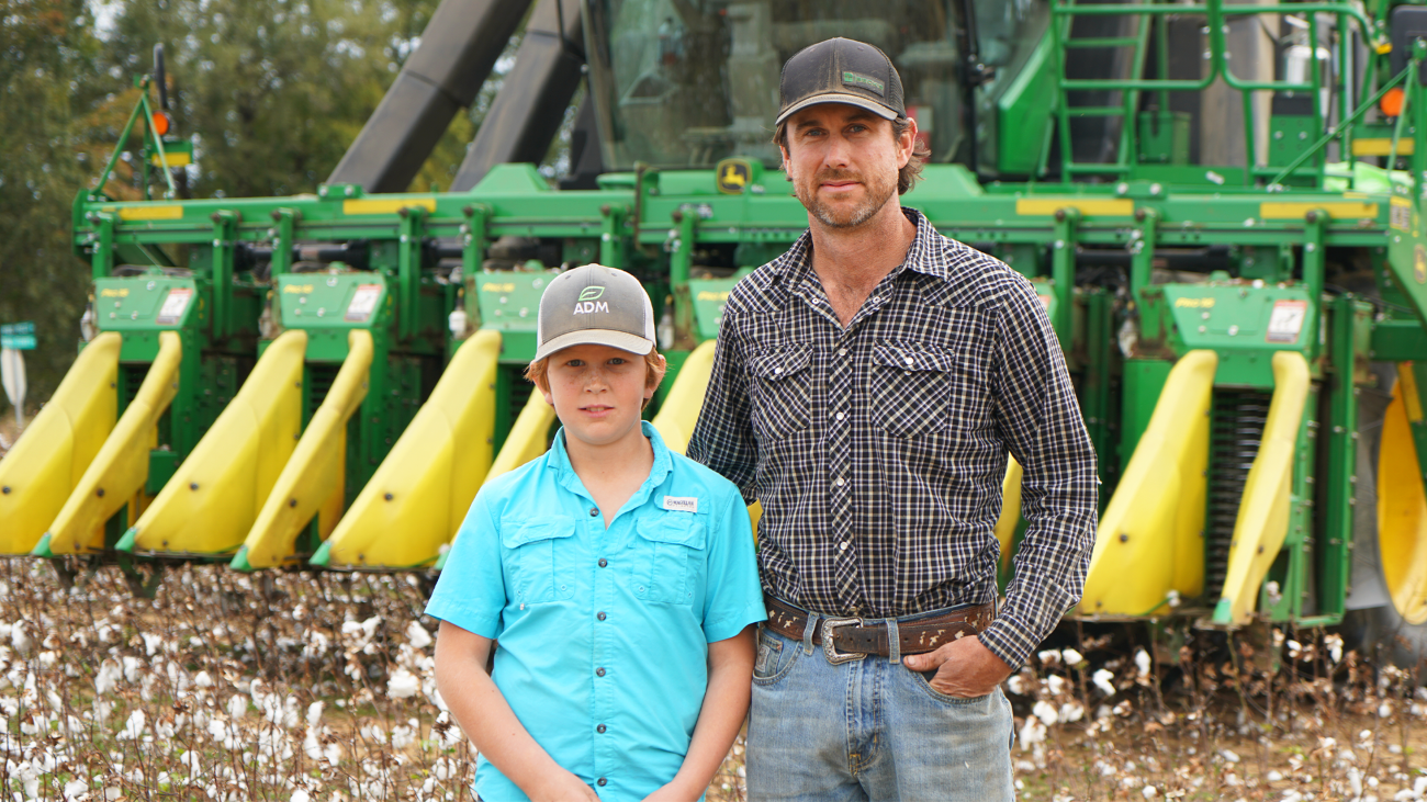 Scott Farmer and his son standing in front of farm machinery,