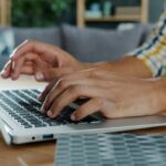 Close-up of a man's hands typing on a keyboard.