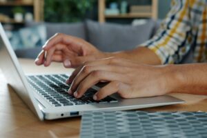 Close-up of a man's hands typing on a keyboard.
