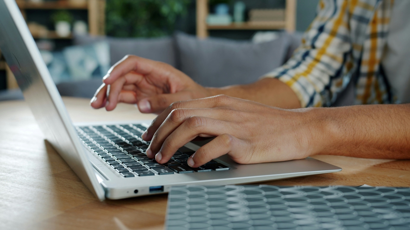 Close-up of a man's hands typing on a keyboard.