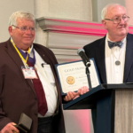 Mark Windham receives a certificate on stage as both men pose for a photo