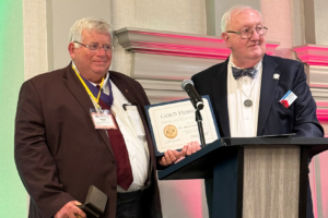 Mark Windham receives a certificate on stage as both men pose for a photo