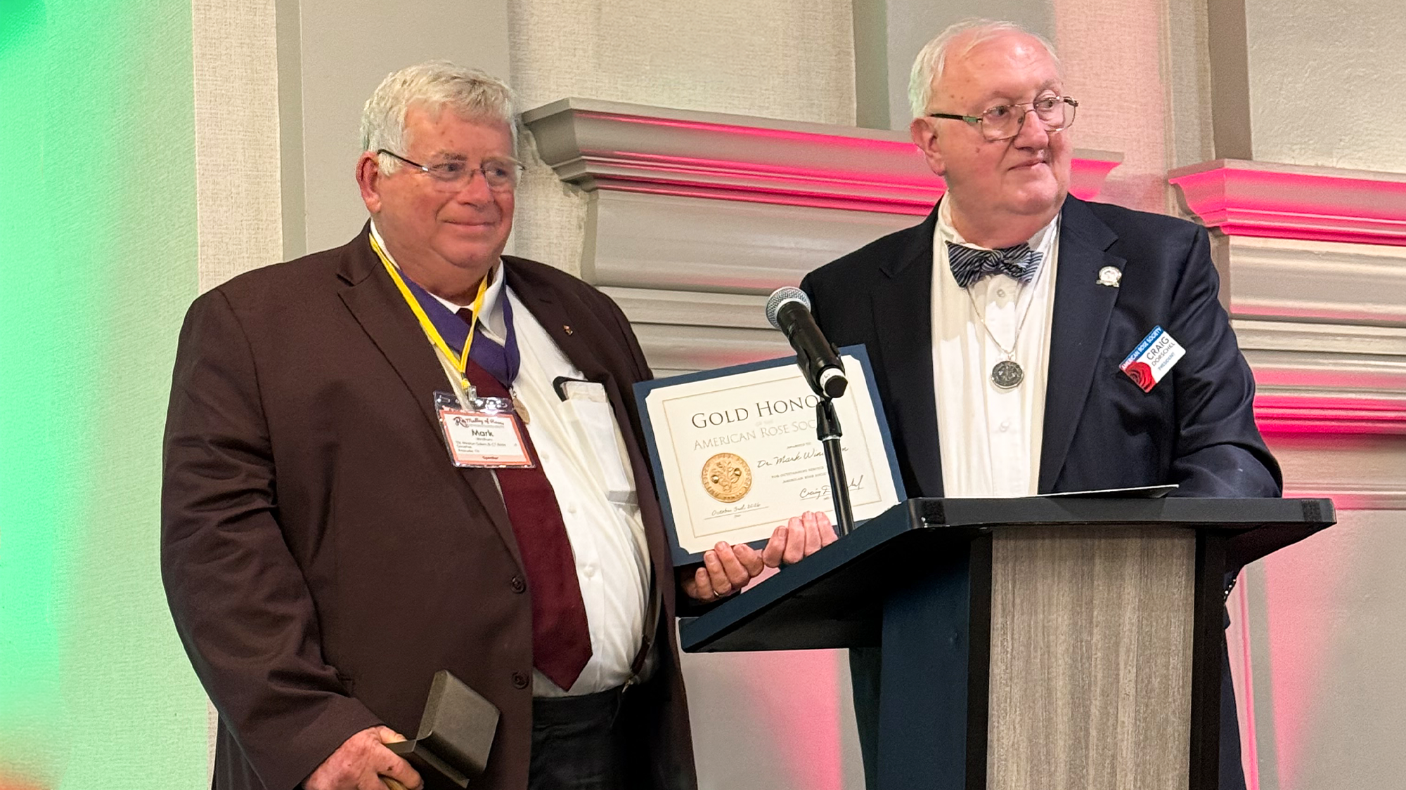 Mark Windham receives a certificate on stage as both men pose for a photo